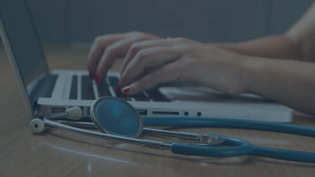 doctor typing on laptop with stethoscope in the foreground